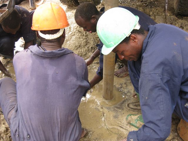 Workers installing water well pipes