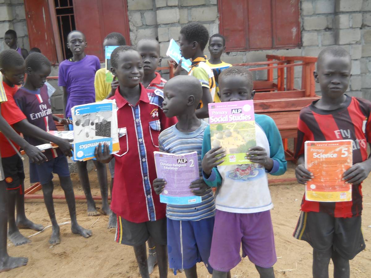 Students holding textbooks provided by Y.E.T. Compassion