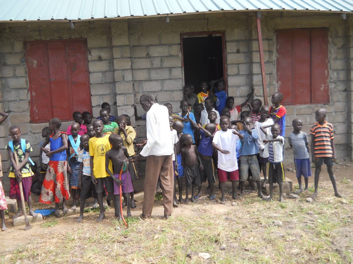 A teacher with students in the Biong community school supported by Y.E.T. Compassion